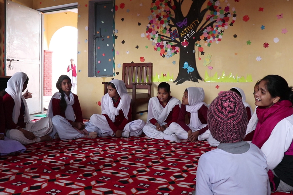 Ananya talking to several young girls in a classroom.